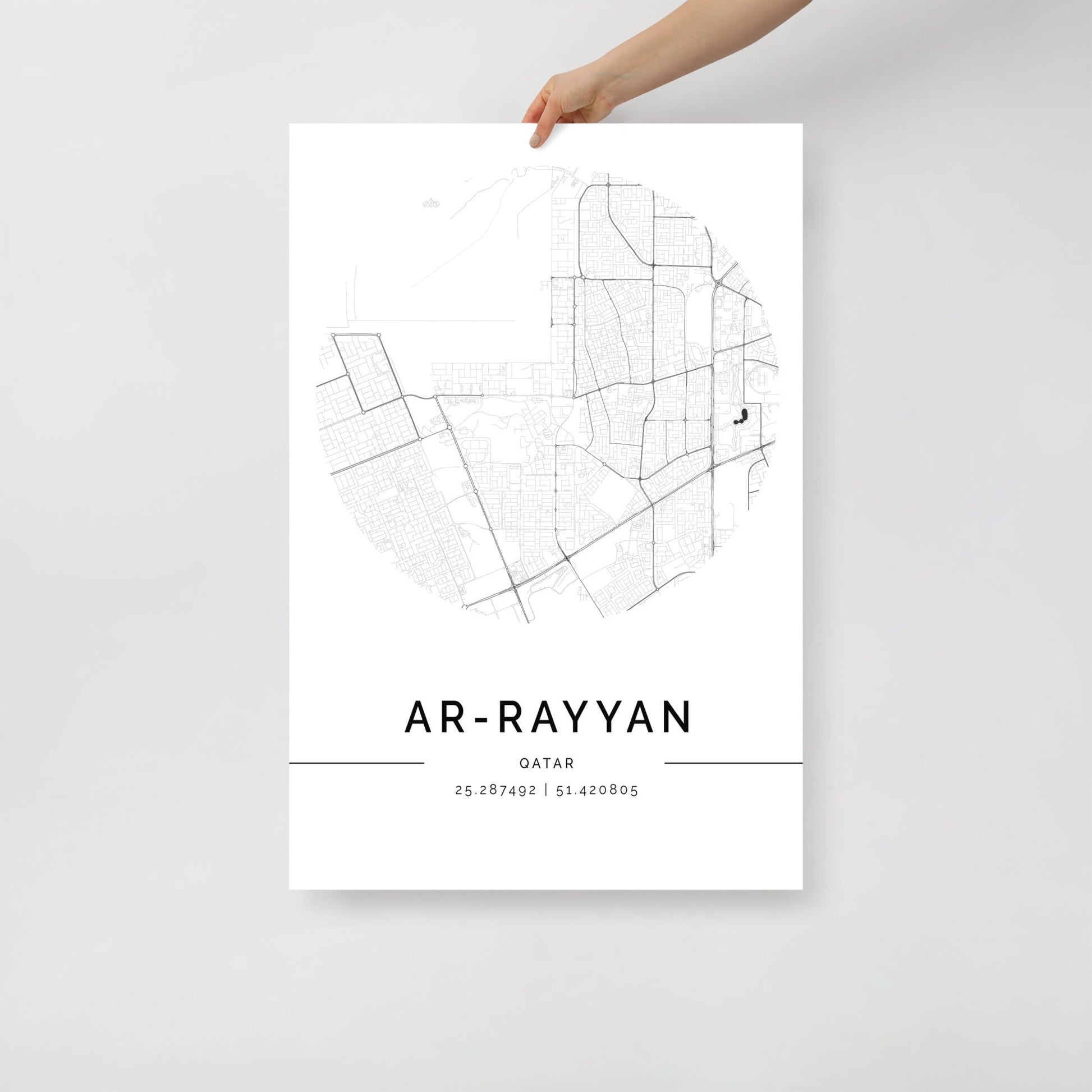 A black and white minimalist map poster of Ar-Rayyan city, held by a hand against a white background.