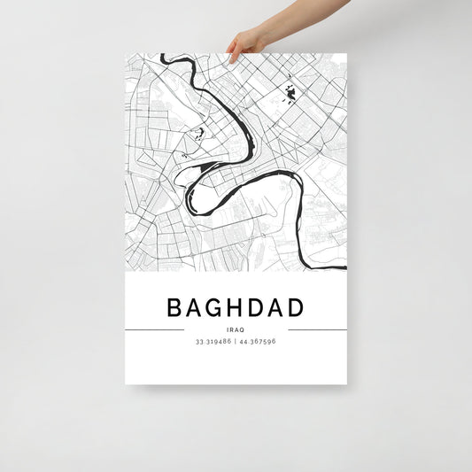 A person holds a minimalist Baghdad Map poster from FN Prints, showcasing a black and white street layout with a distinct river. This wall art print includes geographic coordinates at the bottom, making it ideal for accentuating the city's historic landmarks in your decor.