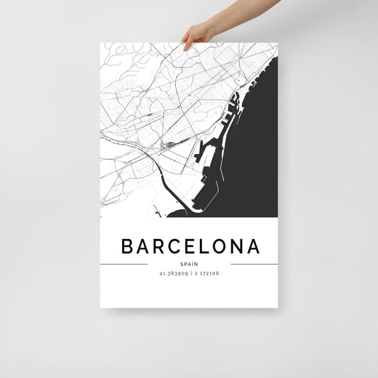 A person is holding the Barcelona City Map by FN Prints, a minimalistic wall art poster in black and white that depicts the major roads and coastal outlines of Barcelona, Spain. The design includes the geographical coordinates: 41.389909, 2.172106, below the print showcasing the city's architectural beauty.