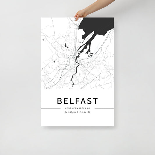 A hand displays the elegant Belfast City Map poster print by FN Prints, showcasing a minimalist black and white depiction of major streets and waterways as wall art. The coordinates (54.597414, -5.934181) are stylishly presented at the bottom of the design.