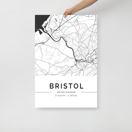 A hand holds a sophisticated black and white Bristol City Map by FN Prints, featuring intricate street and river lines. This urban design wall art includes the text "Bristol, United Kingdom" alongside the coordinates "51.454740 | -2.587692," making it an ideal addition to any home decor.