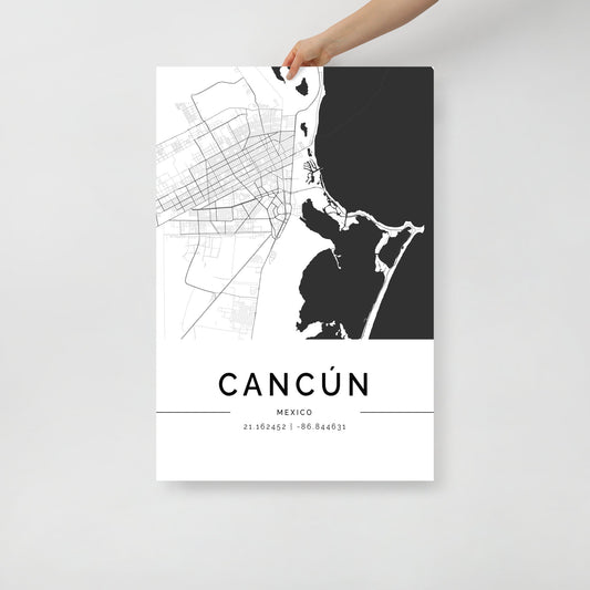 In their hands, someone holds the Cancun City Map by FN Prints, a striking black and white representation of Cancún, Mexico. This minimalist wall art print is designed with sleek elements and prominently features the city's coordinates at the bottom.