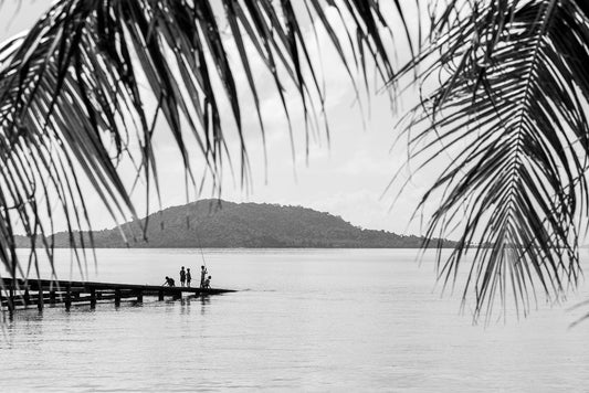 Kid casting their fishing rods of a jetty in Thailand as seen from the beach.