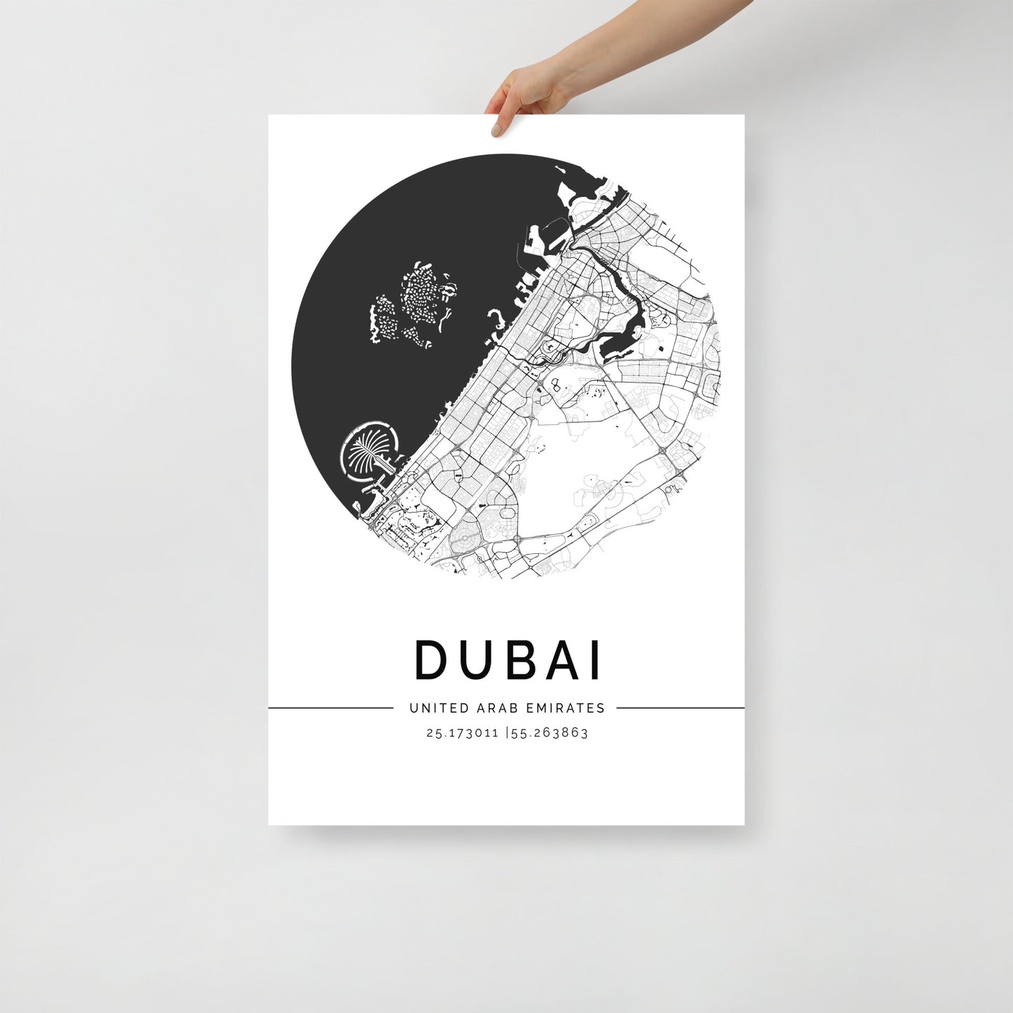 A hand displays the FN Prints Dubai Map poster, made from premium-quality paper. This minimalist piece of contemporary wall art features a black and white map of Dubai, United Arab Emirates, with a circular city layout. The coordinates are elegantly printed below the design.