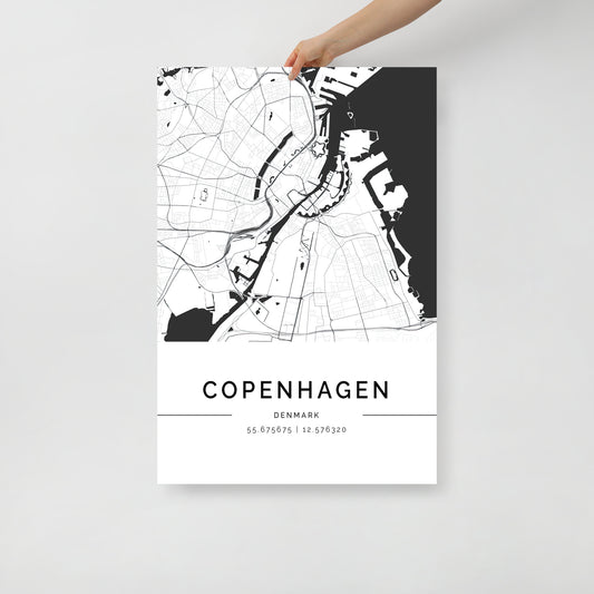 A hand displays the Copenhagen Map from FN Prints, featuring a minimalist black and white design that captures Scandinavian elegance with detailed depictions of the city's streets and waterways, along with Copenhagen’s name and coordinates at the bottom.