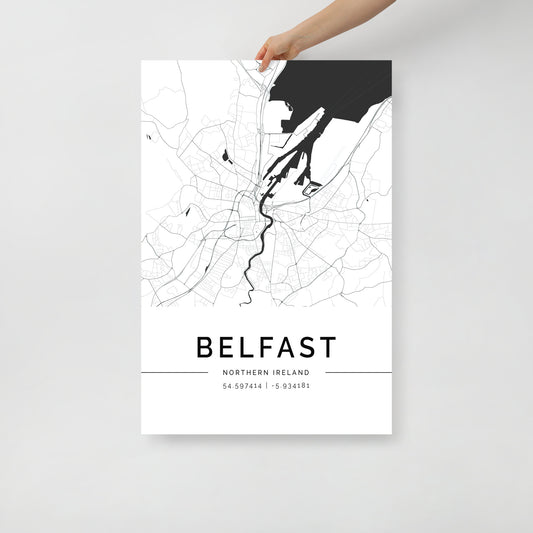 A person holds a Belfast Map by FN Prints, showcasing the historic allure of Northern Ireland's capital in black and white. This wall art features intricate street and river outlines, complete with geographic coordinates at the bottom—ideal for enthusiasts of urban exploration.