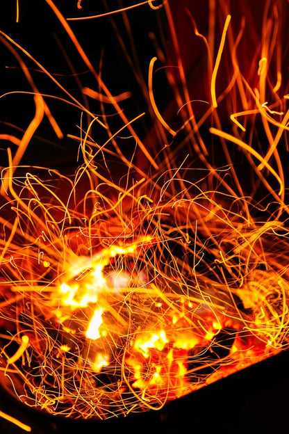 A vibrant display of orange and yellow sparks fly around a glowing fire, set against a dark background. The swirling patterns create a dynamic, abstract composition that captures the intense energy and movement of the firebrands and embers in "Firebrands II," an exquisite photography print by FN Prints.