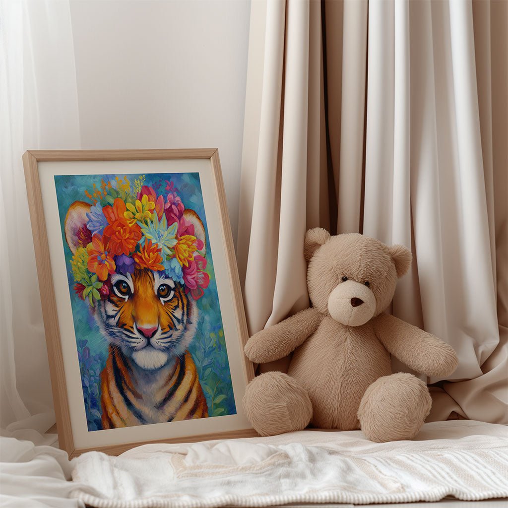 The FN Prints "Floral Tiger" framed wall art features a baby tiger with a colorful flower crown, shown next to a light brown teddy bear on beige fabric—perfect as vibrant animal decor for a nursery.