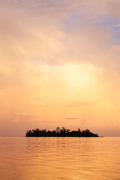Minimalist fine art photography of a small island silhouette on a golden sea under a warm sunset sky in Vietnam.