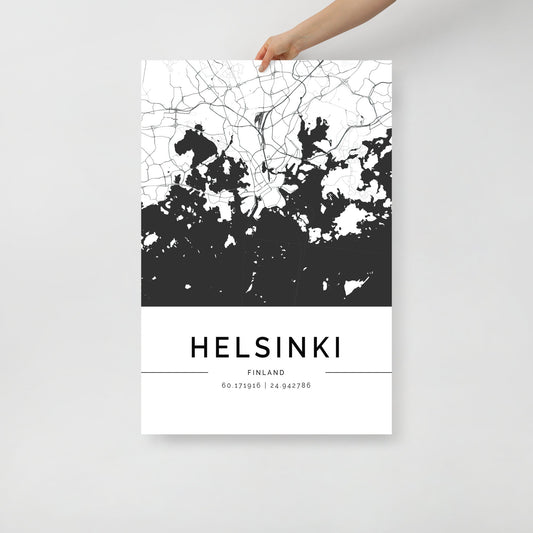 A hand holds a black and white FN Prints Helsinki City Map poster, highlighting Scandinavian Design. The bottom of the striking wall art print features the text "HELSINKI FINLAND" with the geographic coordinates "60.17196 | 24.942786".