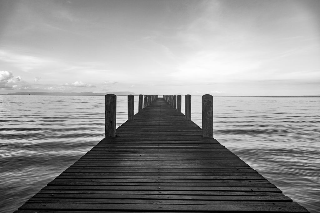 A black and white photograph of a jetty going out to sea