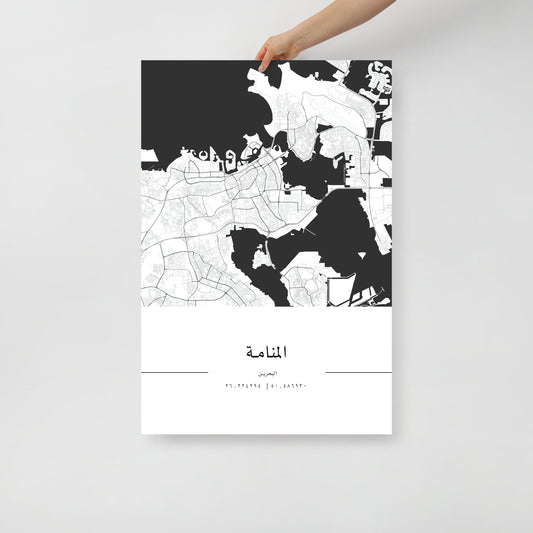 A hand holding a black and white minimalist city map poster of Manama, with sharp details and deep blacks on a white background.
