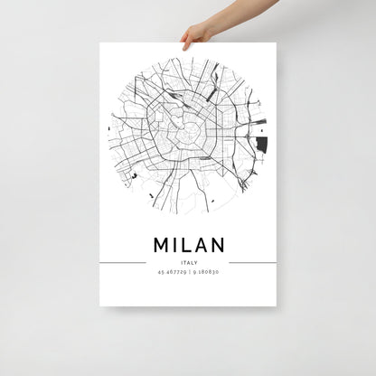 A hand displays a chic wall art piece from FN Prints, showcasing the Milan Map in a sleek black and white circular design. Ideal for urban design enthusiasts, this map features intricate street patterns and coordinates: 45.467729, 9.188030, all with a minimalistic touch.