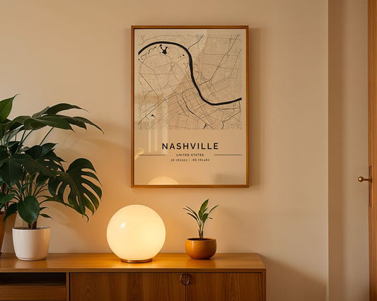 A softly lit room with a wood side table featuring a glowing spherical lamp and two potted plants. Above, an FN Prints Nashville City Map framed on the beige wall adds charm. A closed wooden door on the right complements this cozy corner's Nashville vibe.