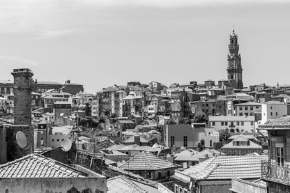 The FN Prints "Porto Rooftops" photograph captures a panoramic view of a densely packed urban neighborhood featuring a mix of historic and modern buildings. In the background, an intricate tower rises above the rooftops, dominating the skyline with its architectural beauty and European elegance.