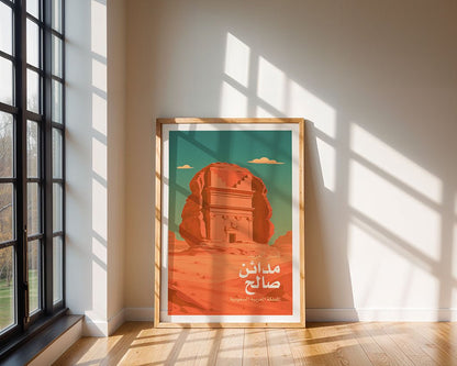 The FN Prints "Qasr al-Farid Madain Saleh" framed poster, with Arabic text and a monument illustration, rests on a wooden floor by a beige wall as sunlight streams in, casting soft shadows.