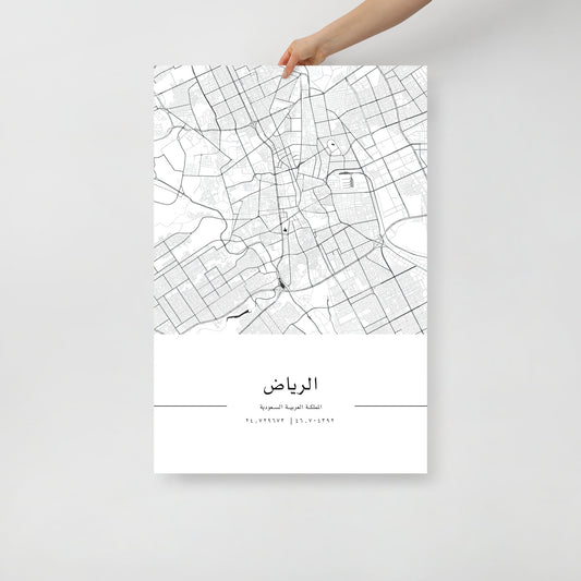 A hand holding a black and white minimalist map poster of Riyadh, Saudi Arabia, with sharp details and deep blacks.
