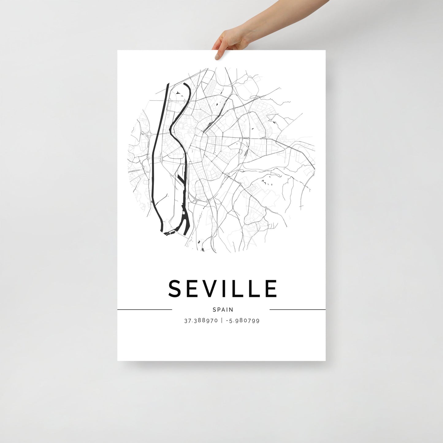 An individual holds a minimalist map poster of Seville, created by FN Prints on premium-grade paper. This sophisticated wall art features intricate street lines and coordinates, with "SEVILLE" prominently showcased at the bottom in bold black and white.