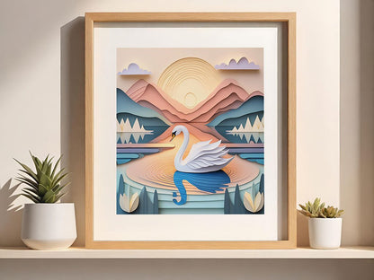 The framed digital artwork, "Sora The Swan" by FN Prints, beautifully captures a white swan gracefully gliding across a tranquil lake. In the background, mountains and the sun add depth to the scene. Crafted using a layered paper art technique in soothing pastel shades, this piece is elegantly showcased on a shelf next to two small potted plants.