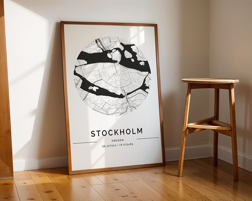 FN Prints' Stockholm City Map poster, featuring a circular black-and-white design with coordinates, leans against a light wall. Perfectly complementing home decor, it sits on hardwood flooring next to a wooden stool.