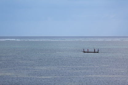 Enjoy the serene maritime adventure captured in 'The Fishermen Colour' by FN Prints, featuring a small boat with three people fishing on a calm, expansive ocean under a cloudy sky. The horizon in the background is faintly visible, elegantly separating the sky from the sea and enhancing the coastal charm of their tranquil outing.