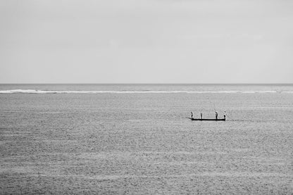 Photograph: "The Fishermen Black & White" by FN Prints captures three people standing on a long, narrow boat in the middle of a calm sea. The horizon is visible with a thin line of waves in the background, and the sky appears overcast. This scene of maritime adventure exudes tranquility as sea and sky blend seamlessly together.