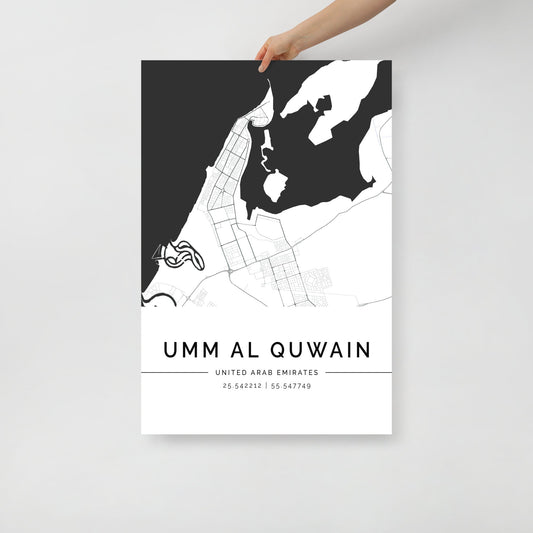 A person is holding an FN Prints minimalist luxury wall art print of the Umm Al Quwain City Map, showcasing a simple black and white design with geographic coordinates at the bottom, elegantly highlighting the coastal layout of the area in the United Arab Emirates.