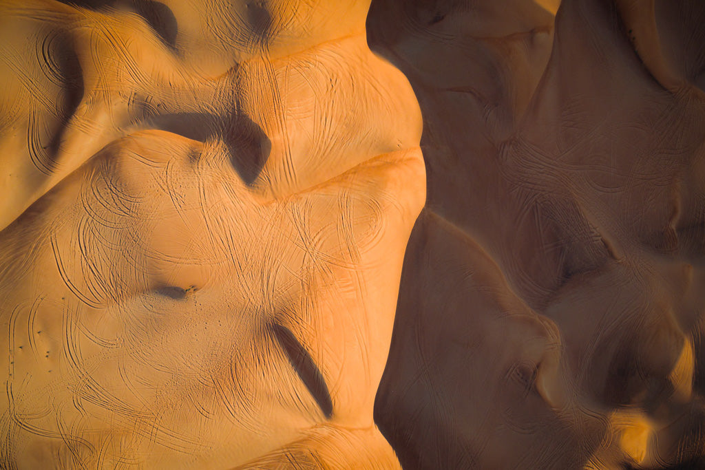 Aerial photograph of golden sand dunes in a desert, with intricate patterns and shadows created by the wind. The flowing lines and smooth curves of the dunes highlight the natural beauty and texture of the landscape, perfect for off-road adventures, as captured in FN Prints' "Dune Part III Colour.